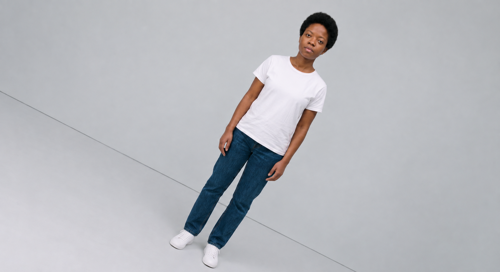 Tipos de ângulo: dutch angle (ângulo holandês). Uma mulher ao centro da imagem, usando calça jeans e camiseta branca, enquadrada com a câmera inclinada