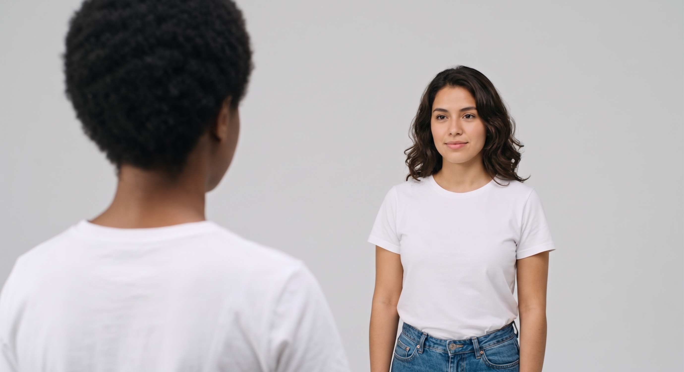 Tipos de plano: plano sobre os ombros. Duas mulheres, uma de costas e uma de frente para a outra em um fundo neutro